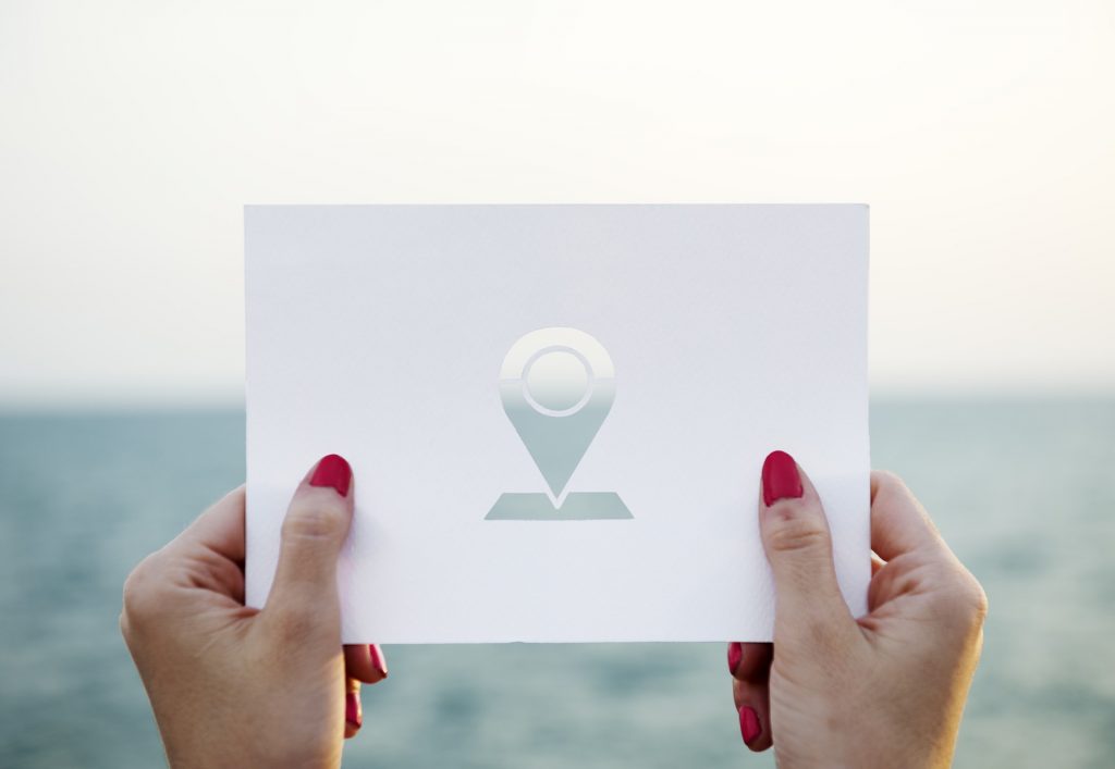 Frauenhände halten ein ausgeschnittenes Papier vor das Meer.